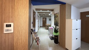 A hallway with wooden paneling, a blue ceiling, a white refrigerator, and a potted plant. - Charim Guesthouse (Seoul)