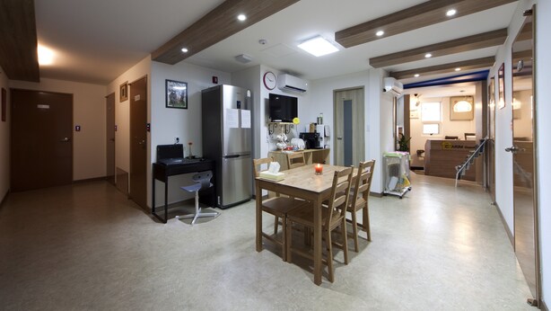 A modern kitchen with a dining area, wooden beams on the ceiling, and a refrigerator. - Charim Guesthouse (Seoul)