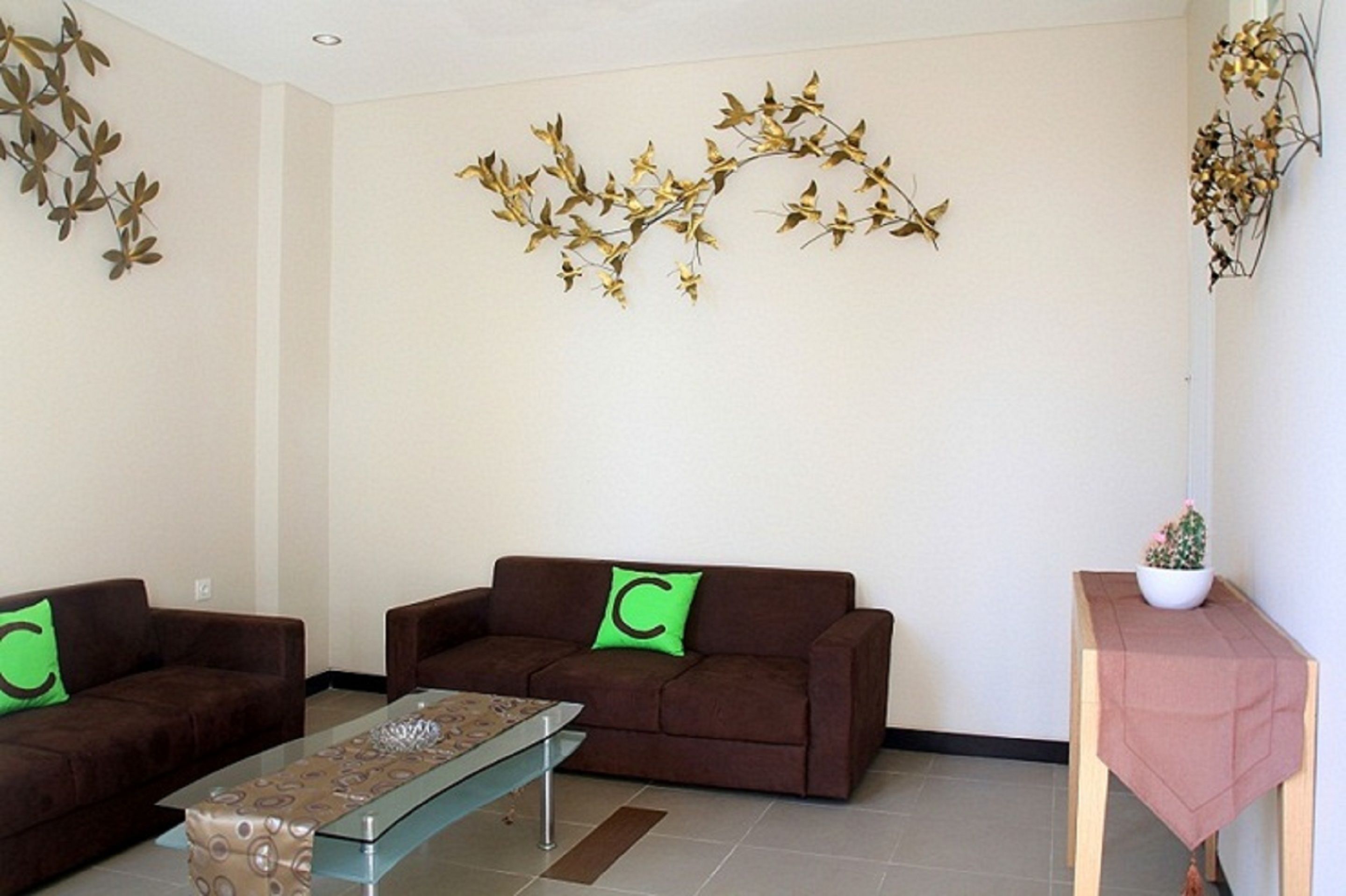 A living room with two brown sofas, a glass coffee table, and a small wooden side table with a plant.
