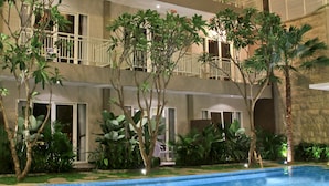 Un hôtel à plusieurs étages doté de balcons, d’une piscine et d’une végétation luxuriante.