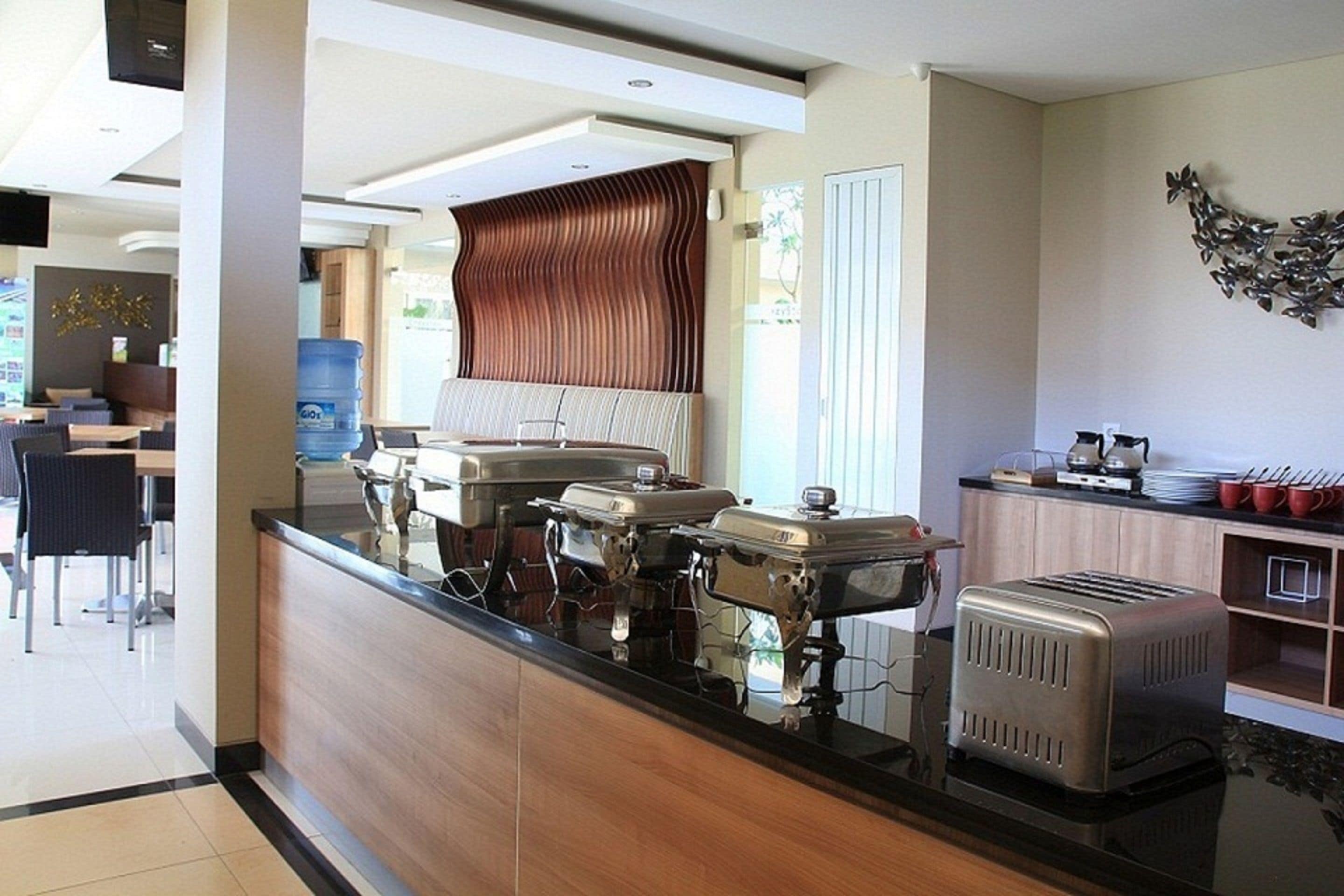 Un vestíbulo de hotel con una recepción, zona de buffet y área de descanso.