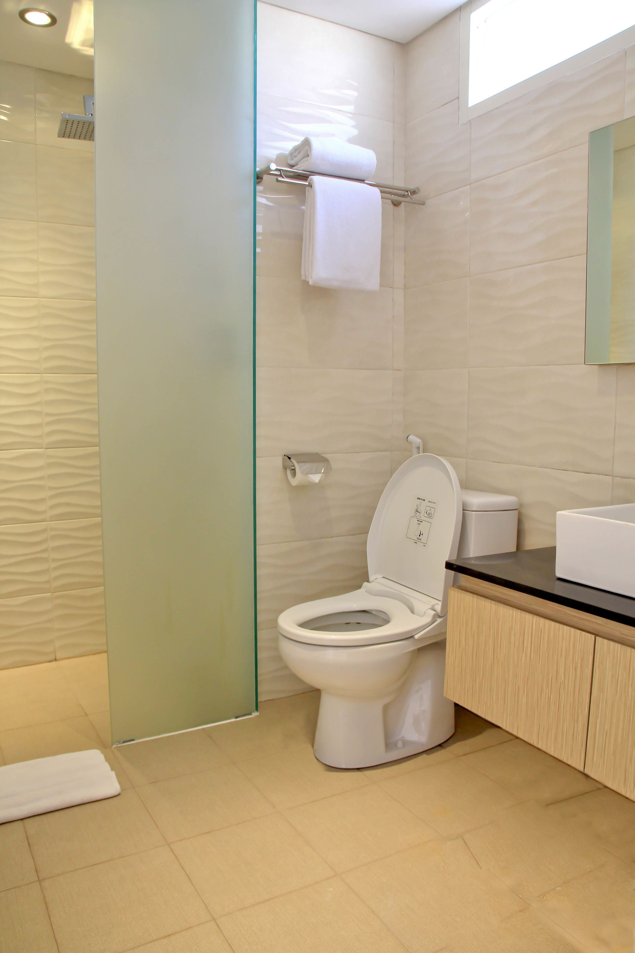 A modern bathroom with a glass shower enclosure, a toilet with a control panel, and a wooden vanity with a mirror.