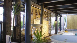 A covered outdoor area with a decorative lantern, a stone planter with flowers, and a wooden structure. - Hotel Les Champs Jiaosi (Jiaoxi)
