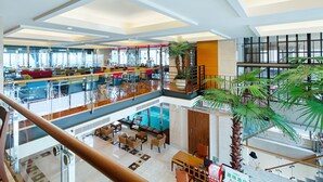 A spacious hotel lobby with multiple seating areas, a central staircase, and a large indoor palm tree. - Hotel Les Champs Jiaosi (Jiaoxi)