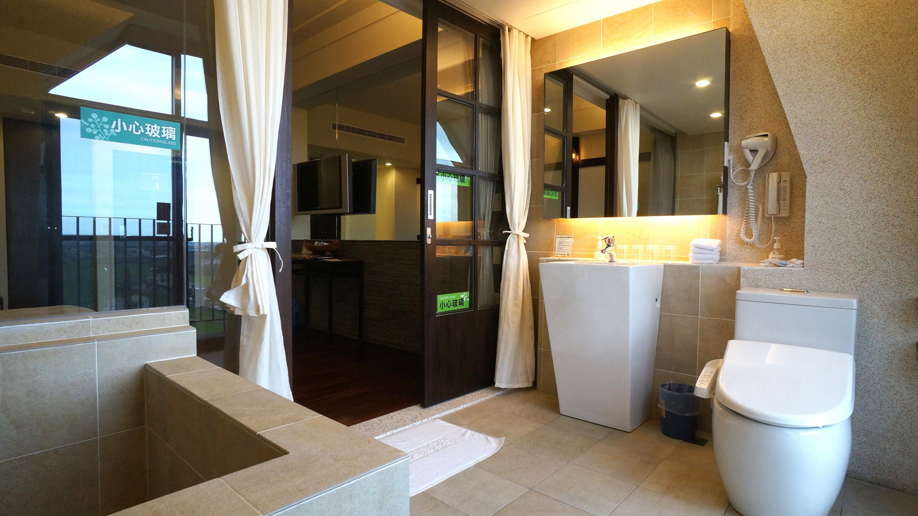 A hotel bathroom with a toilet, sink, and shower area.