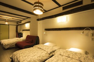 A hotel room with two beds, a red chair, and a wooden ceiling.