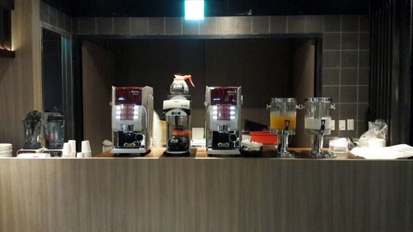 Una estación de café con varias máquinas de café y un dispensador de zumo.