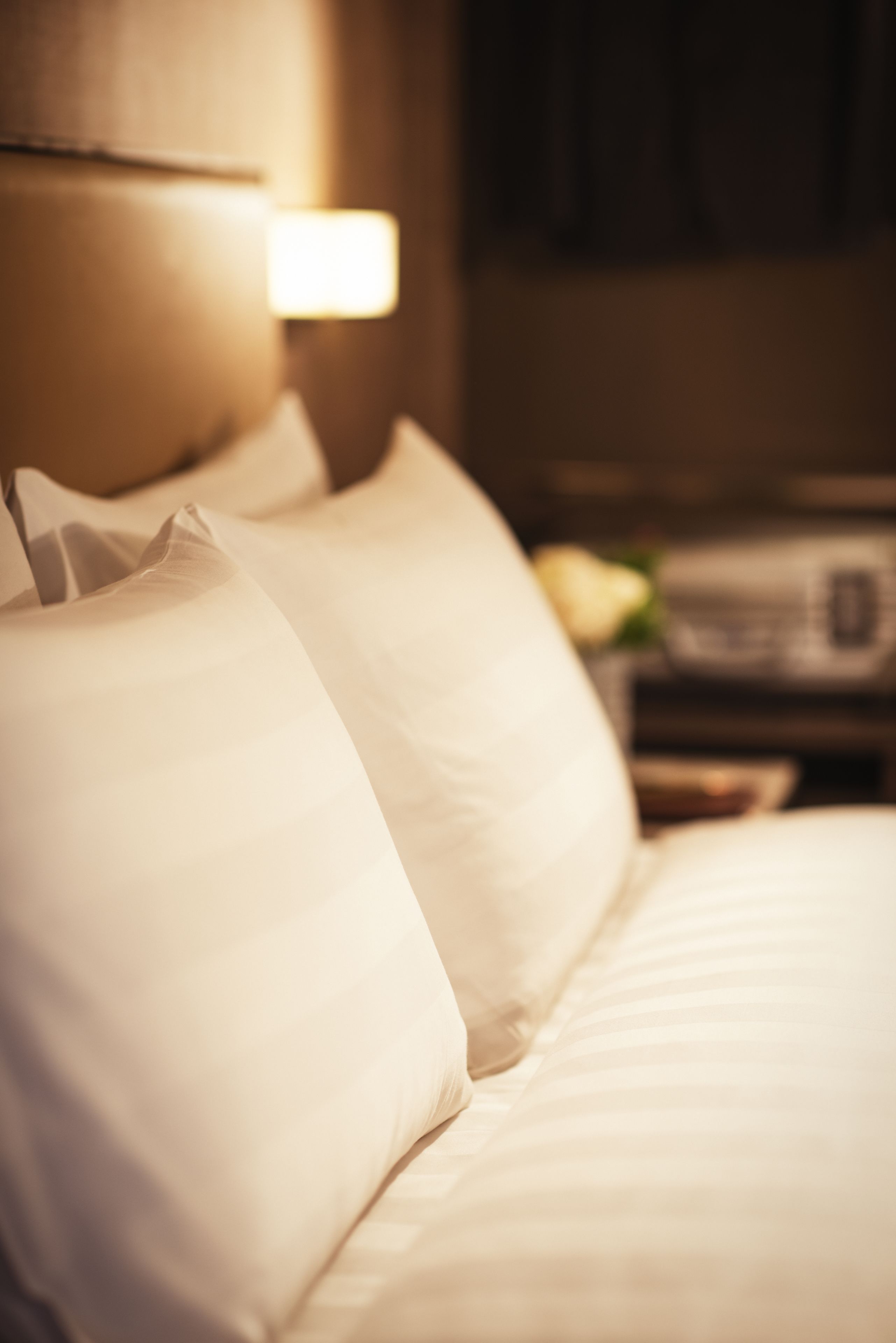 A neatly made bed with white linens and a headboard.