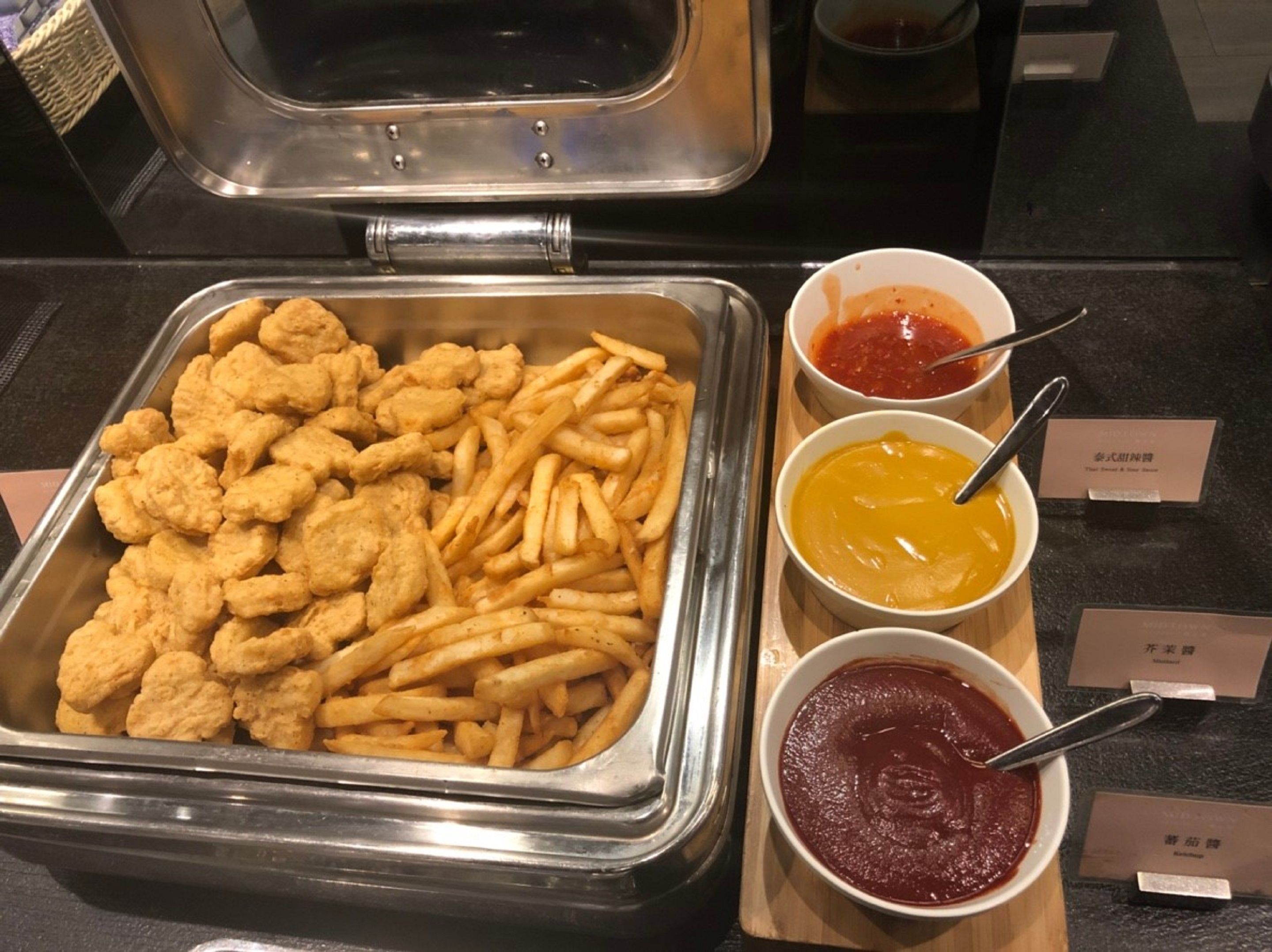 Ein Buffet mit gebratenem Hähnchen, Pommes Frites und drei verschiedenen Soßen.