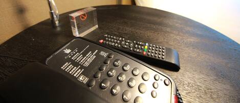 A hotel room with a round table, two remote controls, and a "no smoking" sign.