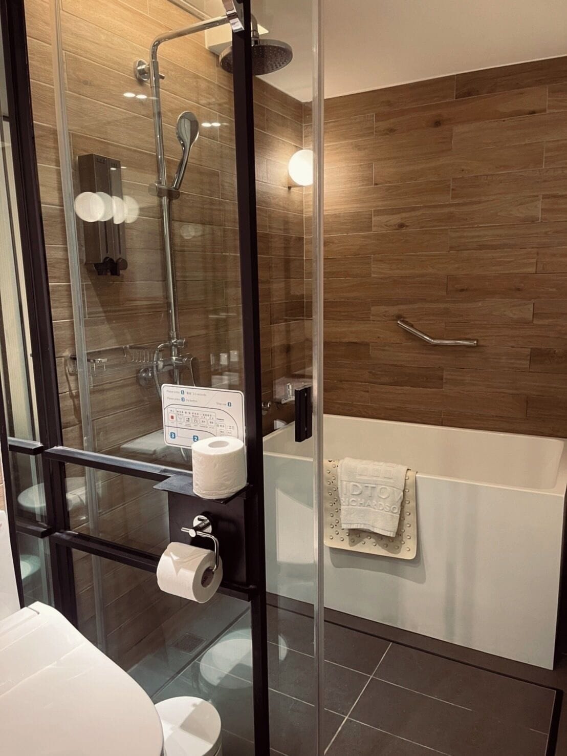 A modern bathroom with a glass shower enclosure, a toilet, and a bathtub.
