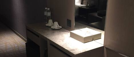 Un baño moderno con encimera de mármol, un espejo y un lavabo pequeño.