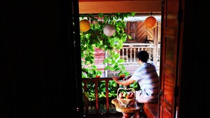 A doorway leading to a room with a wooden bench and a table with a basket of fruit. - Apple Guesthouse (Luang Prabang)