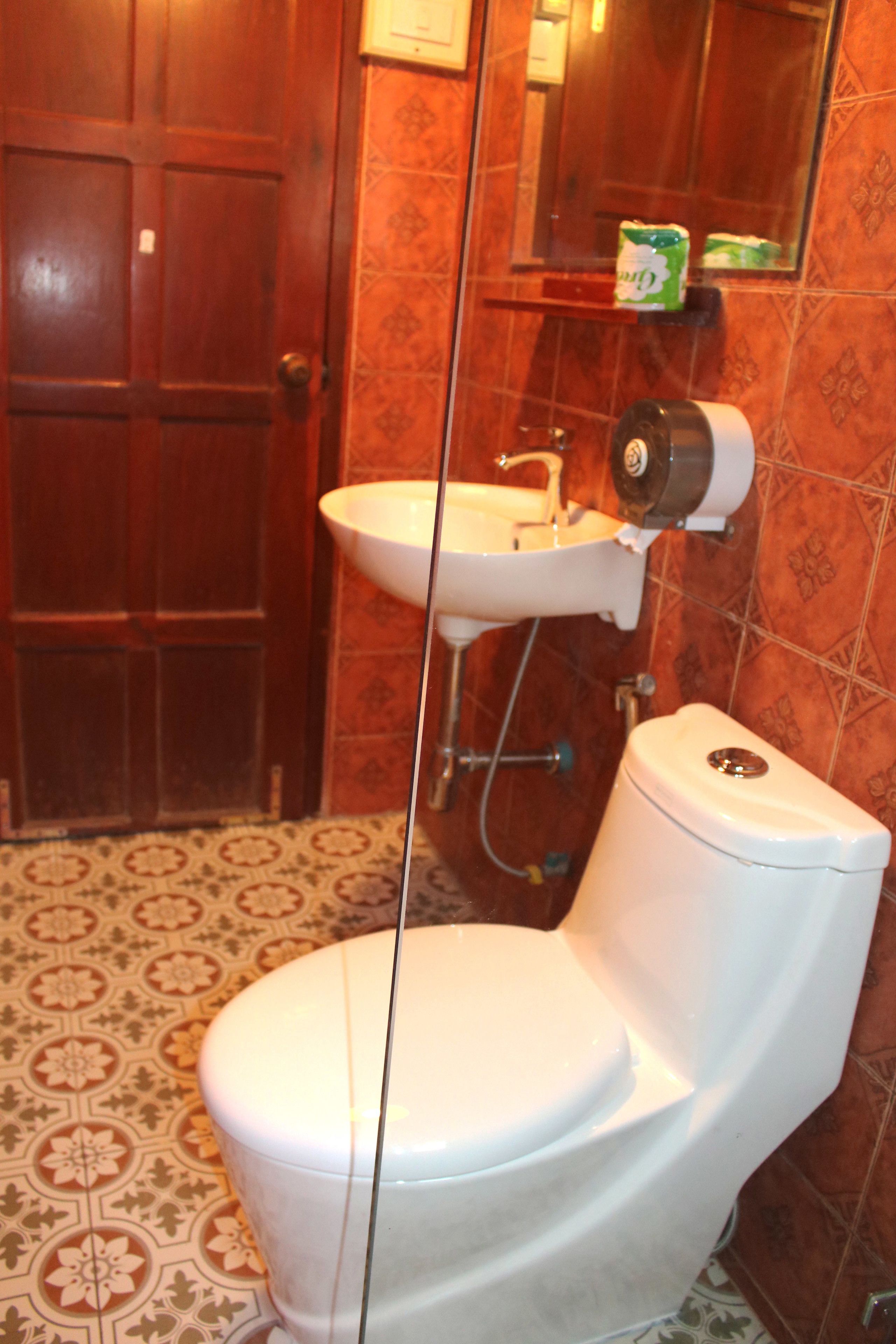 Un baño con inodoro, lavamanos y espejo.