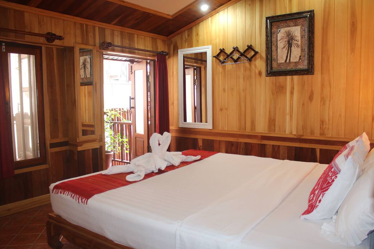 Una habitación con paneles de madera, una cama grande, una toalla roja y un cuadro en la pared.