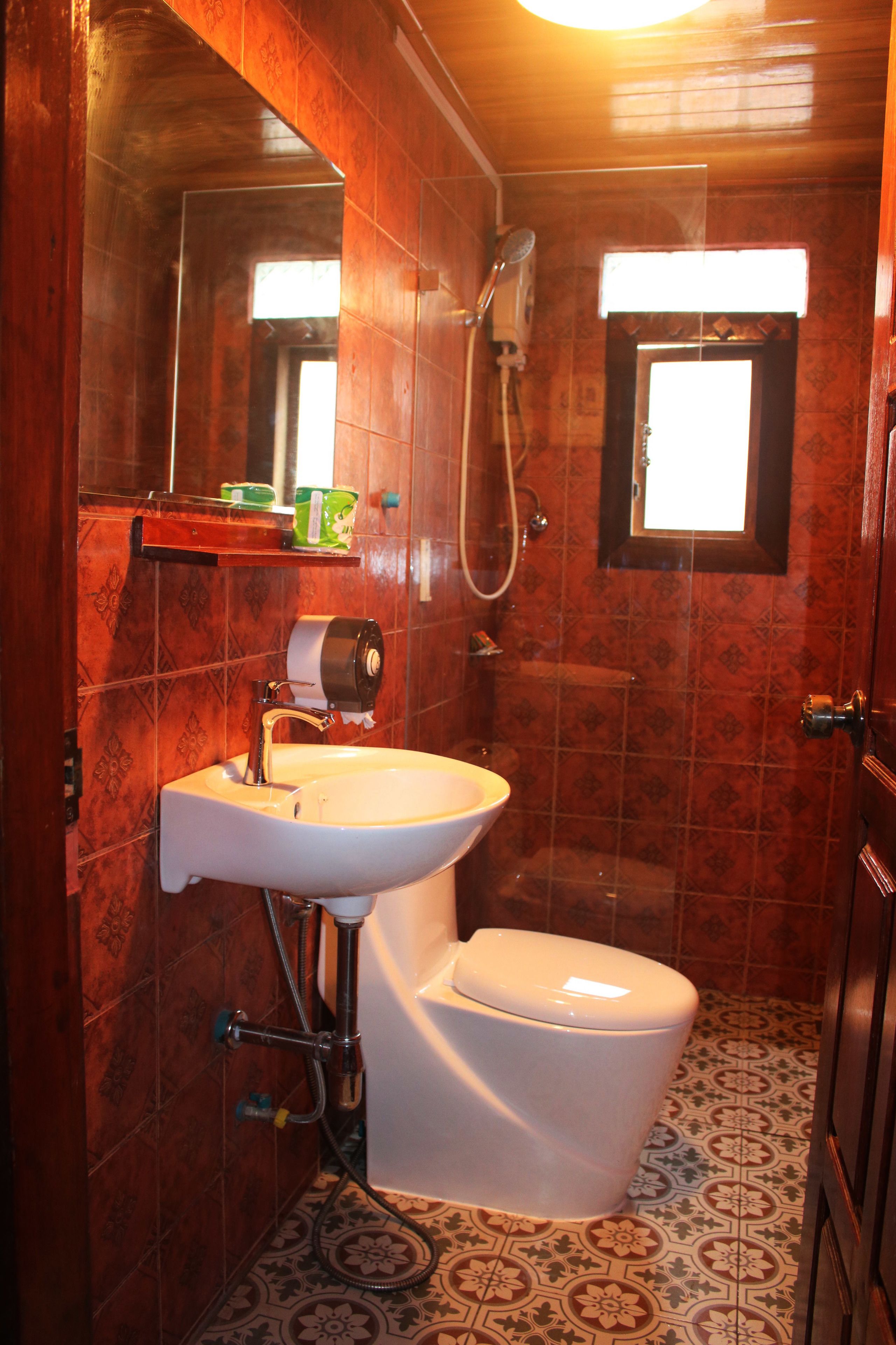 Un baño con lavamanos, inodoro y ducha blancos.