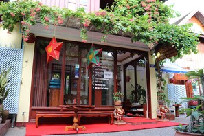 Una casa de huéspedes tradicional con toldo rojo, muebles de madera y adornos colgantes.