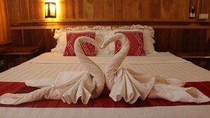 A hotel room with a bed, wooden walls, and a wall-mounted light. - Apple Guesthouse (Luang Prabang)