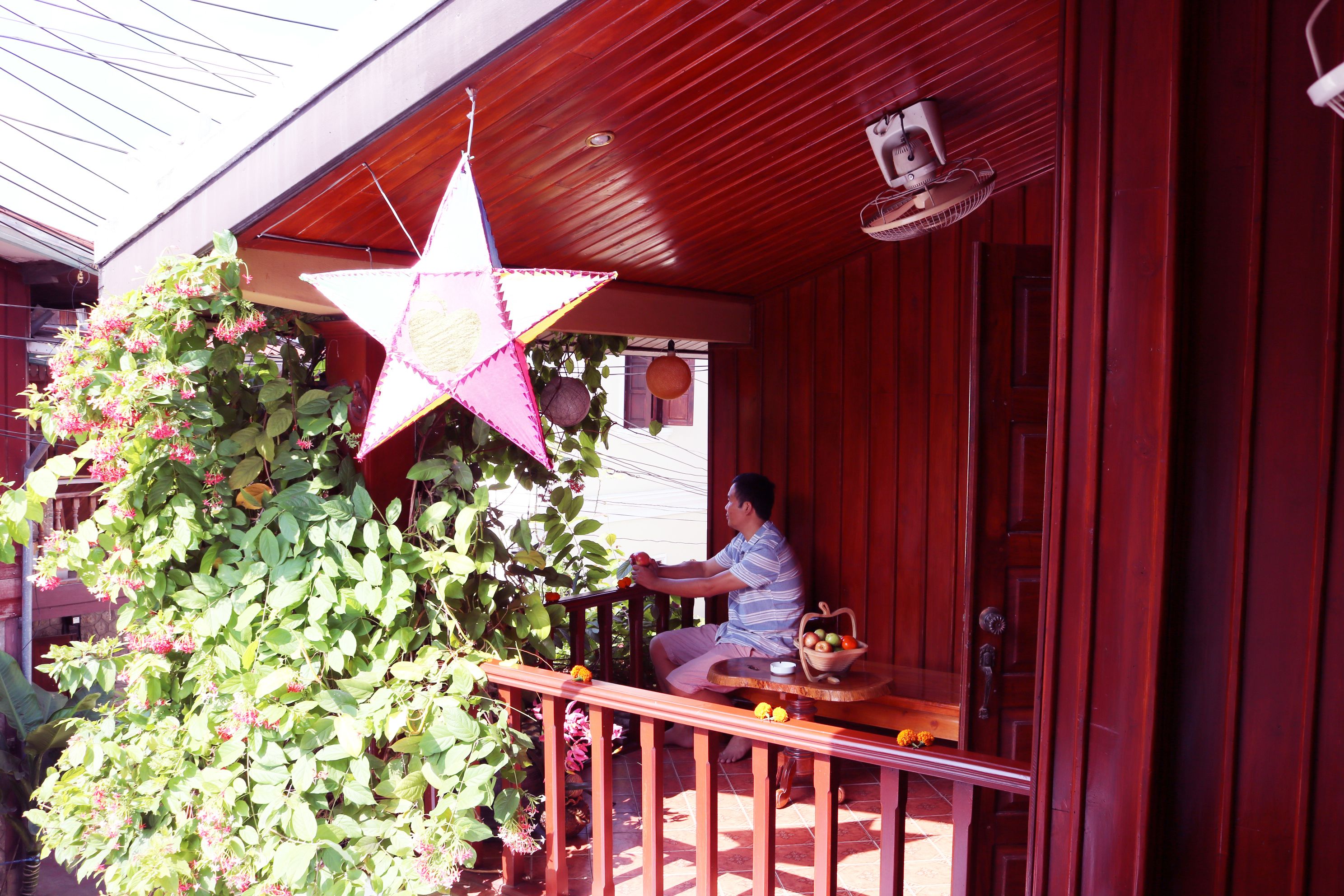 Un porche de madera con un adorno de estrella, una planta en maceta y una mesa con frutas y una cesta.