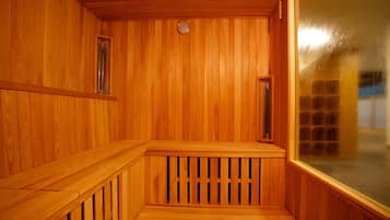 A wooden sauna room with a bench, a window, and a wooden ceiling.