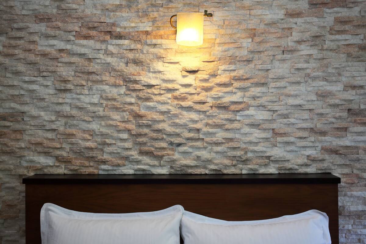 Une chambre avec un mur en pierre et une tête de lit en bois.