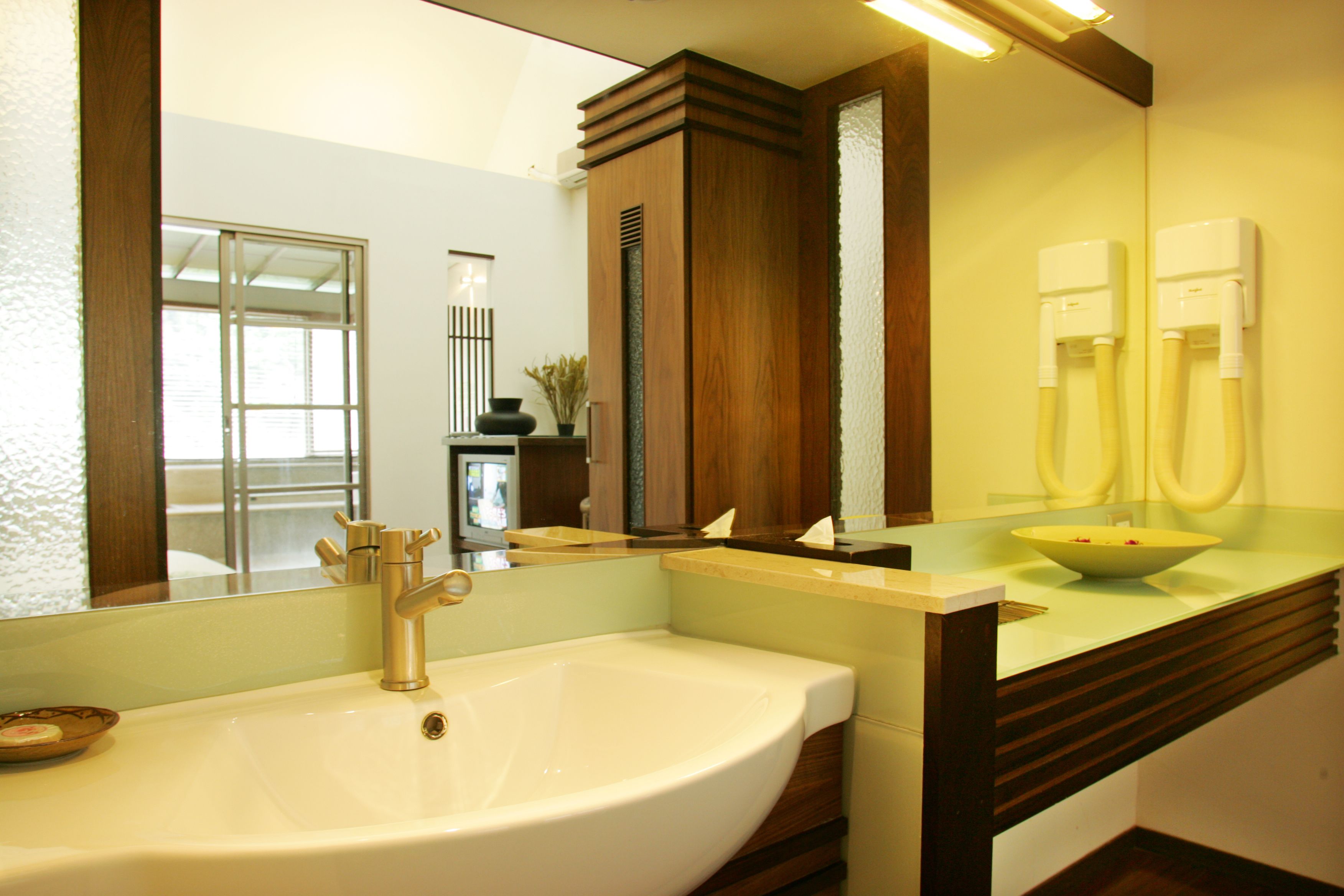 A bathroom with a large sink, a mirror, a wooden cabinet, and a glass countertop.
