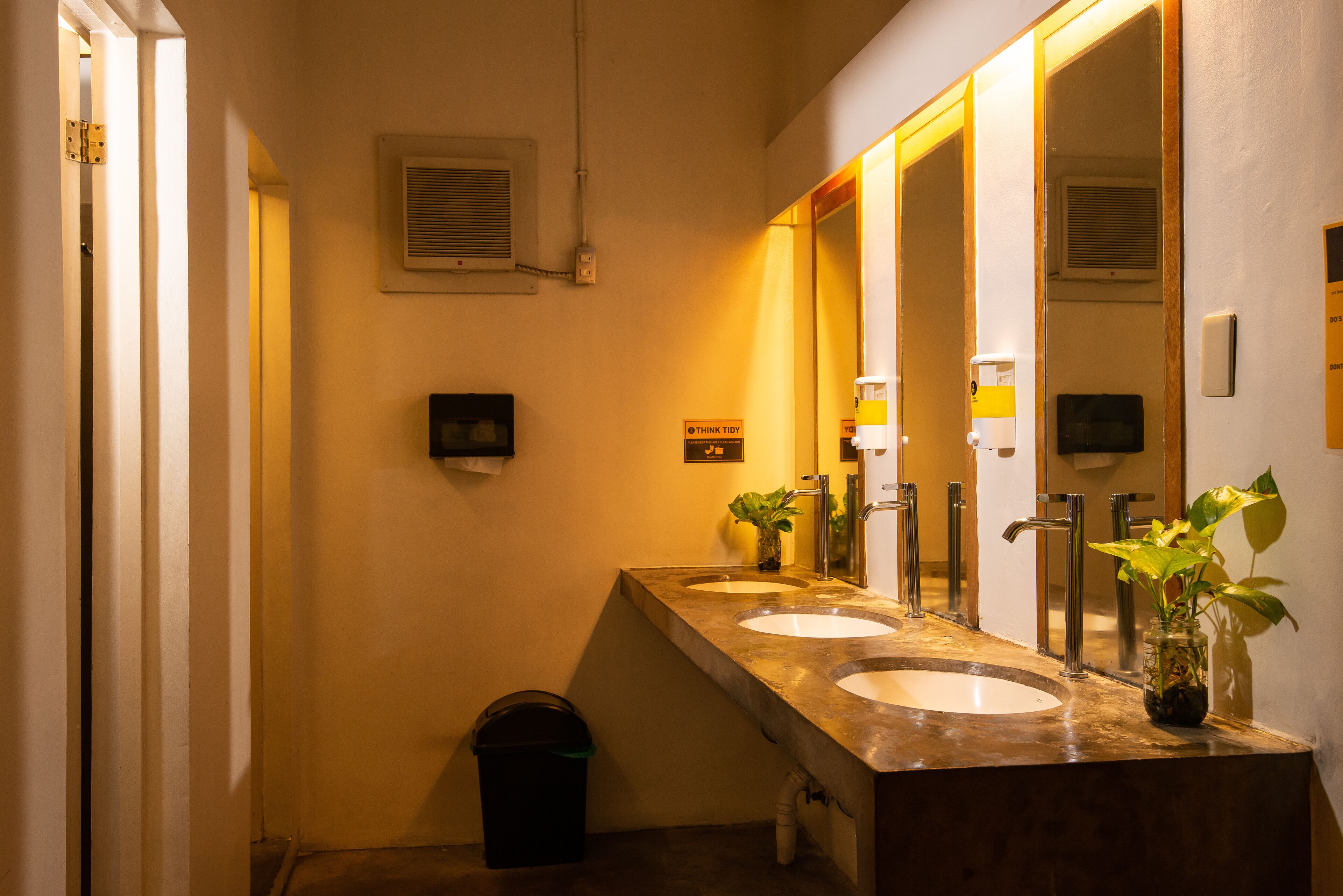 A bathroom with two sinks, a mirror, and a trash bin.
