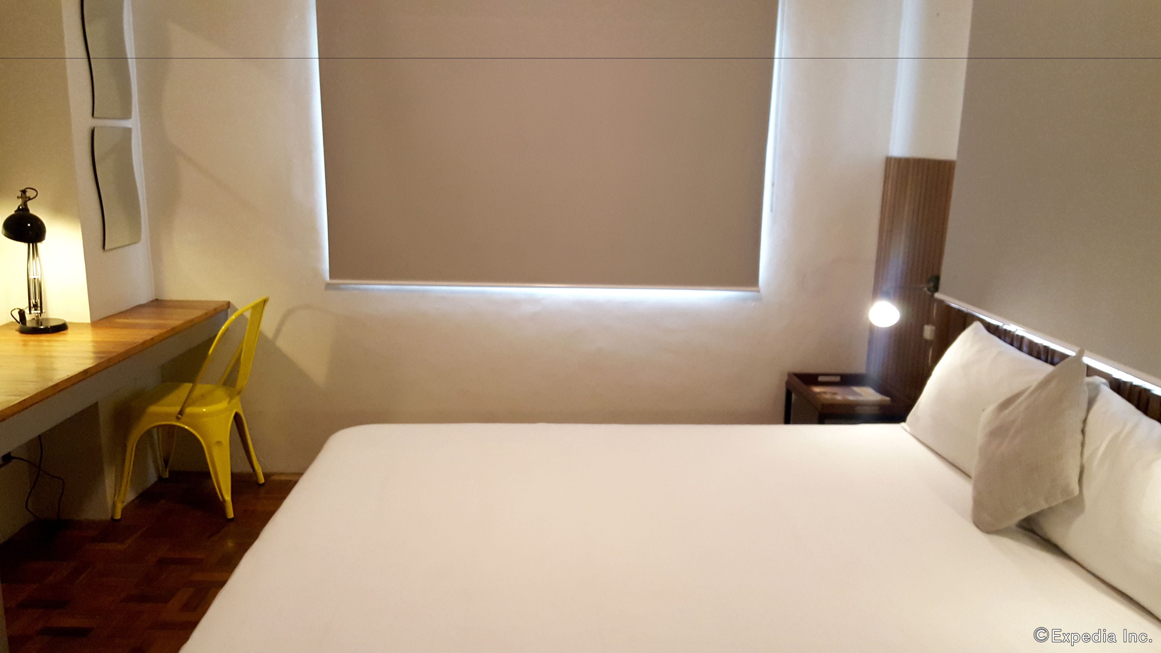 Une chambre d’hôtel avec un lit, un bureau, une chaise et une fenêtre.