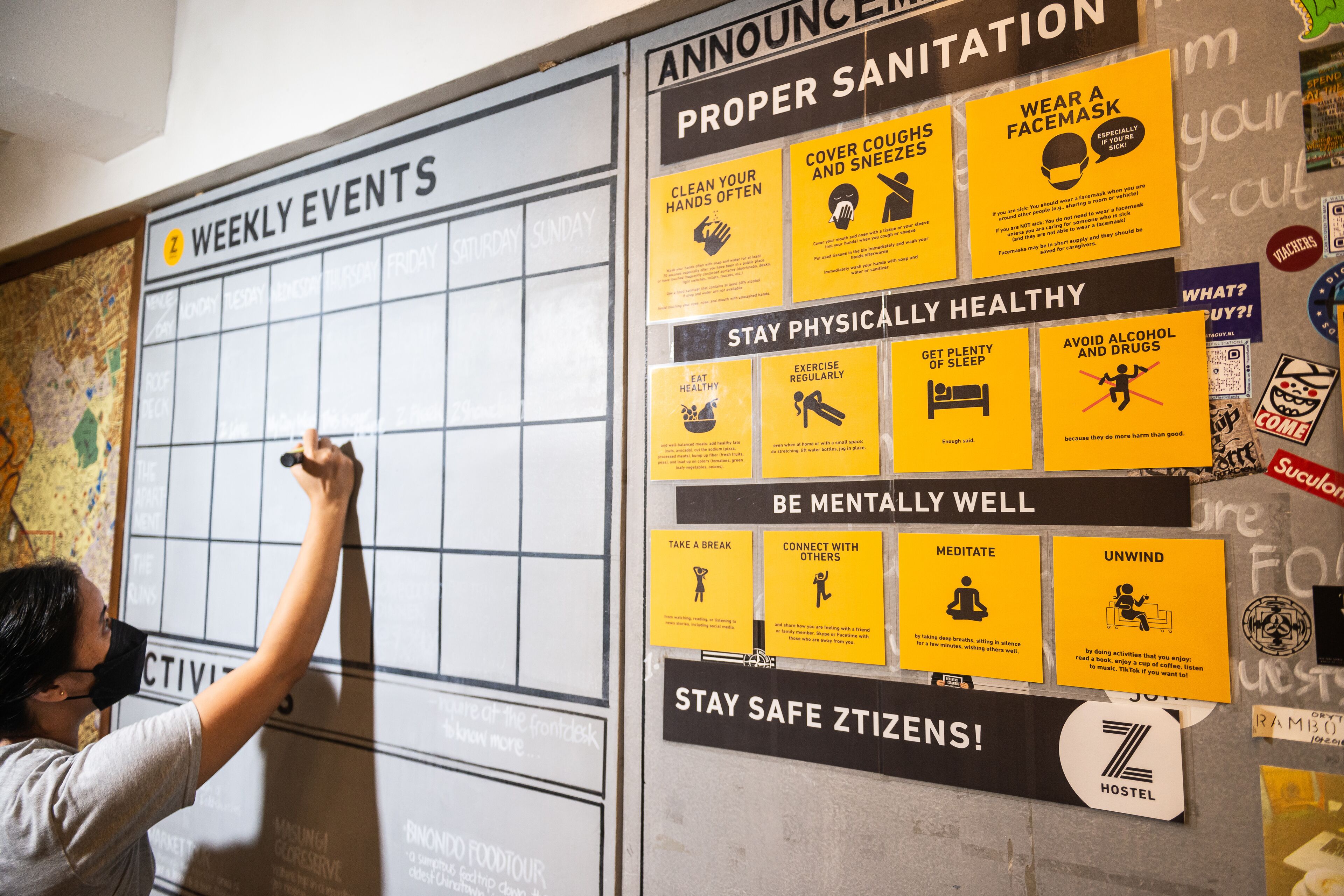 A wall with a weekly events calendar and health and safety posters.