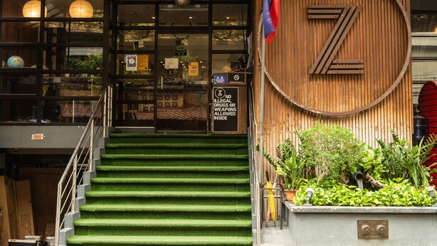 Un escalier aux marches vertes mène à un mur en bois sur lequel est apposé un grand panneau en forme de « Z ».