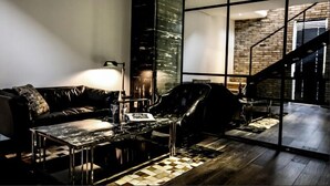 A modern living room with a leather sofa, a glass coffee table, and a view of a brick staircase. - Amare Hotel Jakjeon (Incheon)