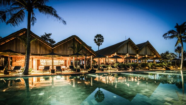 Un resort con piscina, villas de madera y zonas de descanso.