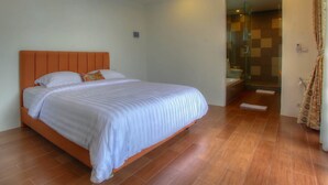 A bedroom with a large bed, a shower area, and a bathroom. - Villa Umah Putih (Canggu)