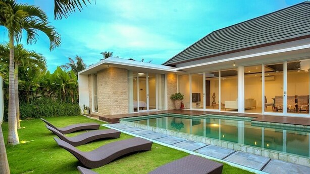A modern house with a swimming pool, a patio with lounge chairs, and a well-maintained garden. - Villa Umah Putih (Canggu)