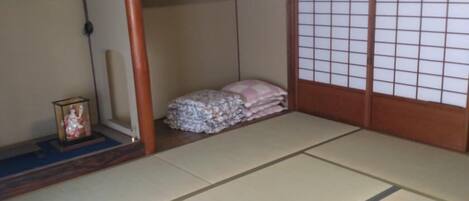 A traditional Japanese room with tatami flooring, a shoji screen, and a small shrine.