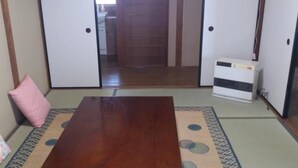 Ein traditioneller japanischer Raum mit Tatami-Boden, einem niedrigen Holztisch und einem Futon.