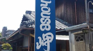 A traditional Japanese building with a blue sign featuring white characters.