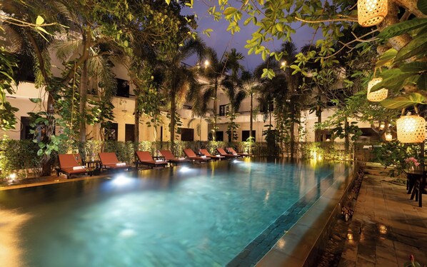 A pool area with lounge chairs and a clear pool, surrounded by greenery and evening lighting. - The Moon Residence & Spa (Siem Reap)