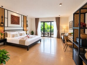 A hotel room with a large bed, a desk, a chair, and a balcony with a view of greenery. - The Moon Residence & Spa (Siem Reap)