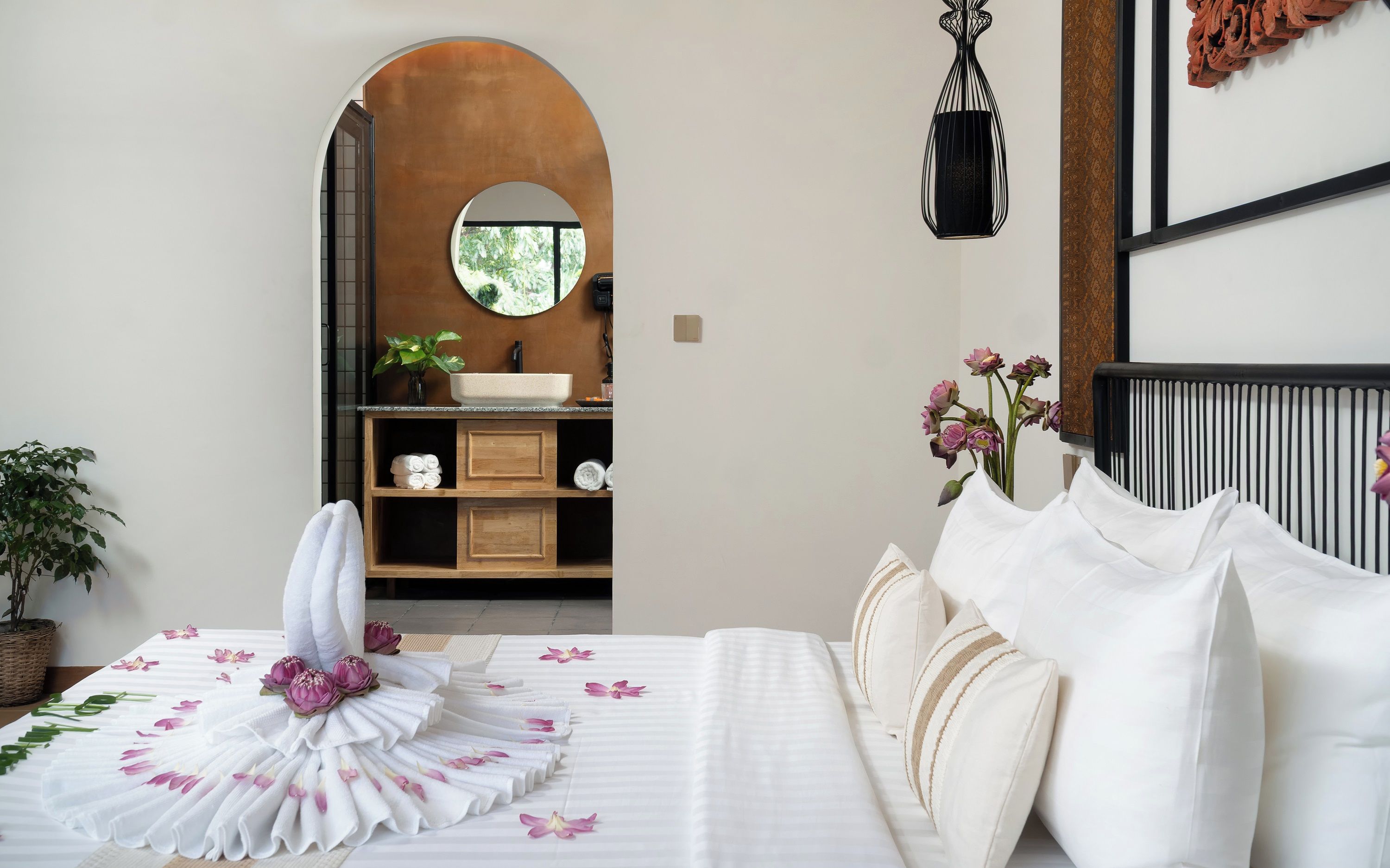 Una habitación de hotel con una cama, un baño con lavamanos y vistas a través de un arco.