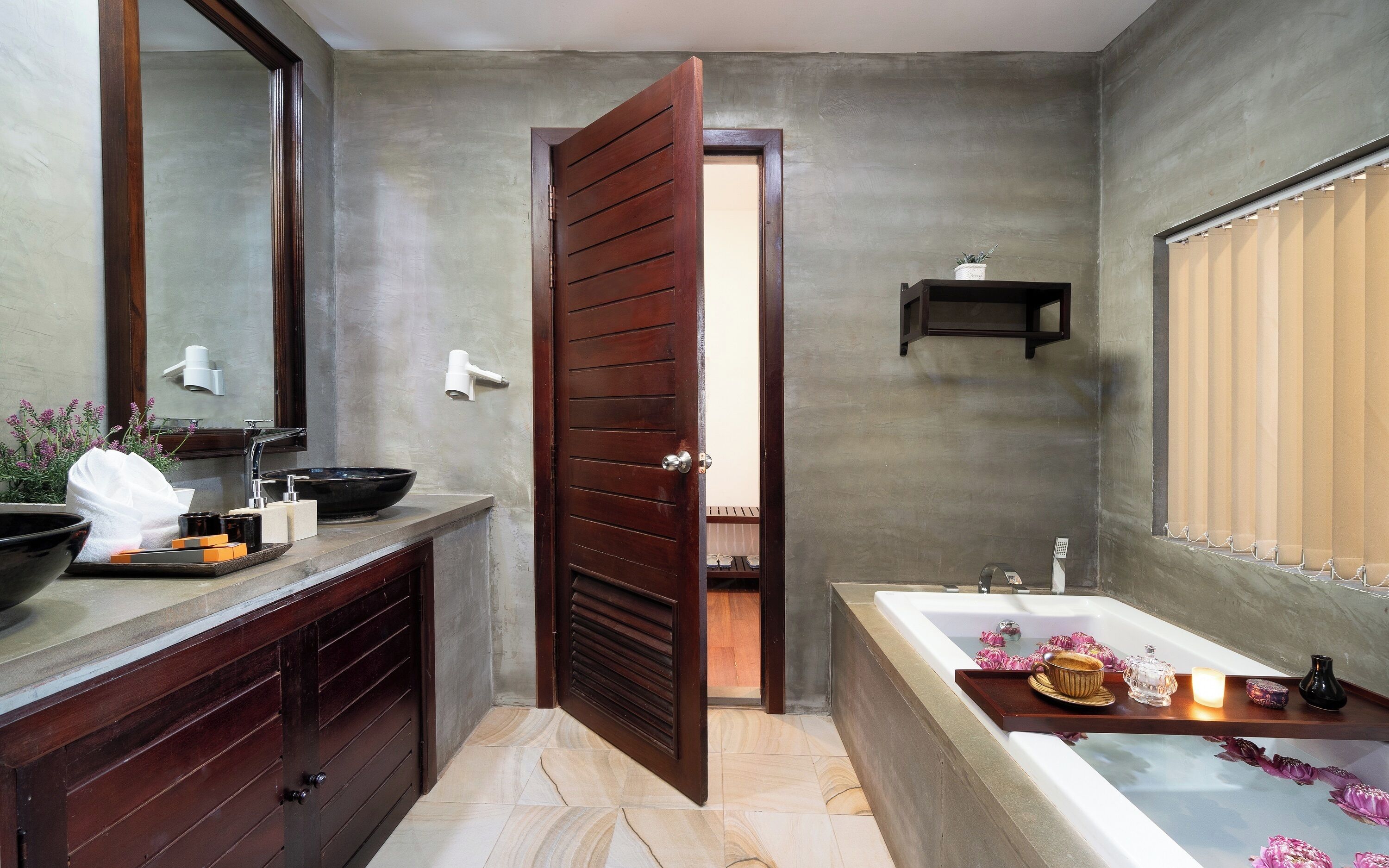 A modern bathroom with a bathtub, a large mirror, a wooden door, and a towel rack.