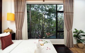 A hotel room with a bed, a nightstand, a lamp, curtains, a window with a view of trees, and a potted plant. - The Moon Residence & Spa (Siem Reap)