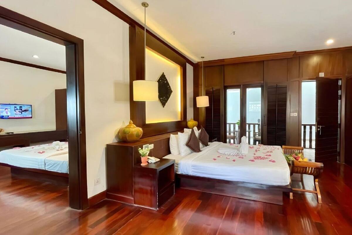 Quarto de hotel com uma cama grande, uma escrivaninha, uma cadeira, uma televisão e uma varanda.