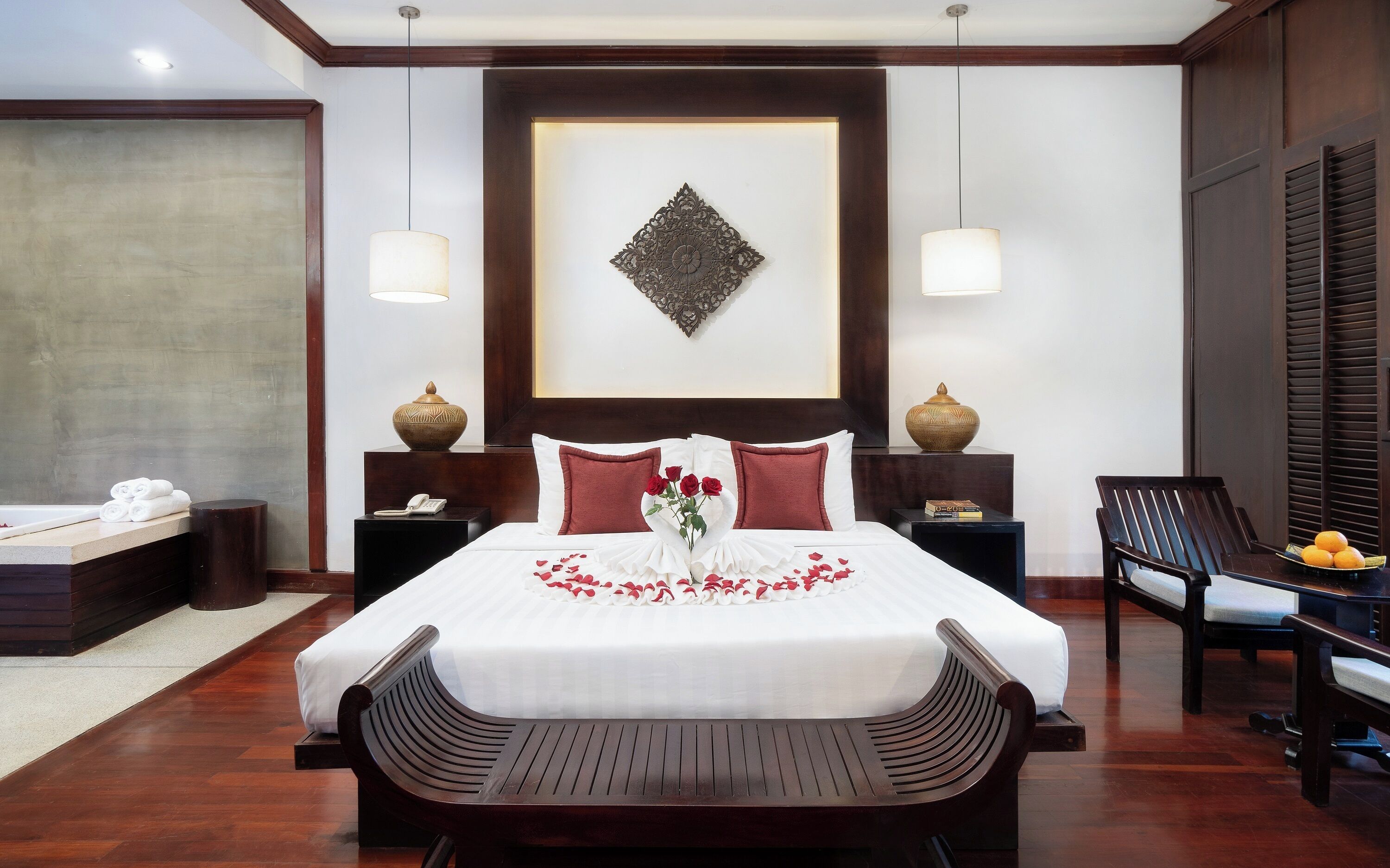 Une chambre d’hôtel avec un grand lit, deux tables de chevet, une chaise et un élément décoratif mural.