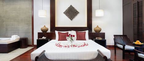 Une chambre d’hôtel avec un grand lit, deux tables de chevet, une chaise et un élément décoratif mural.