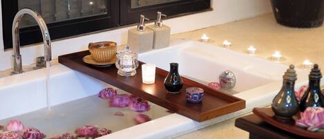 A bathroom with a bathtub, a wooden tray with various items, and candles.