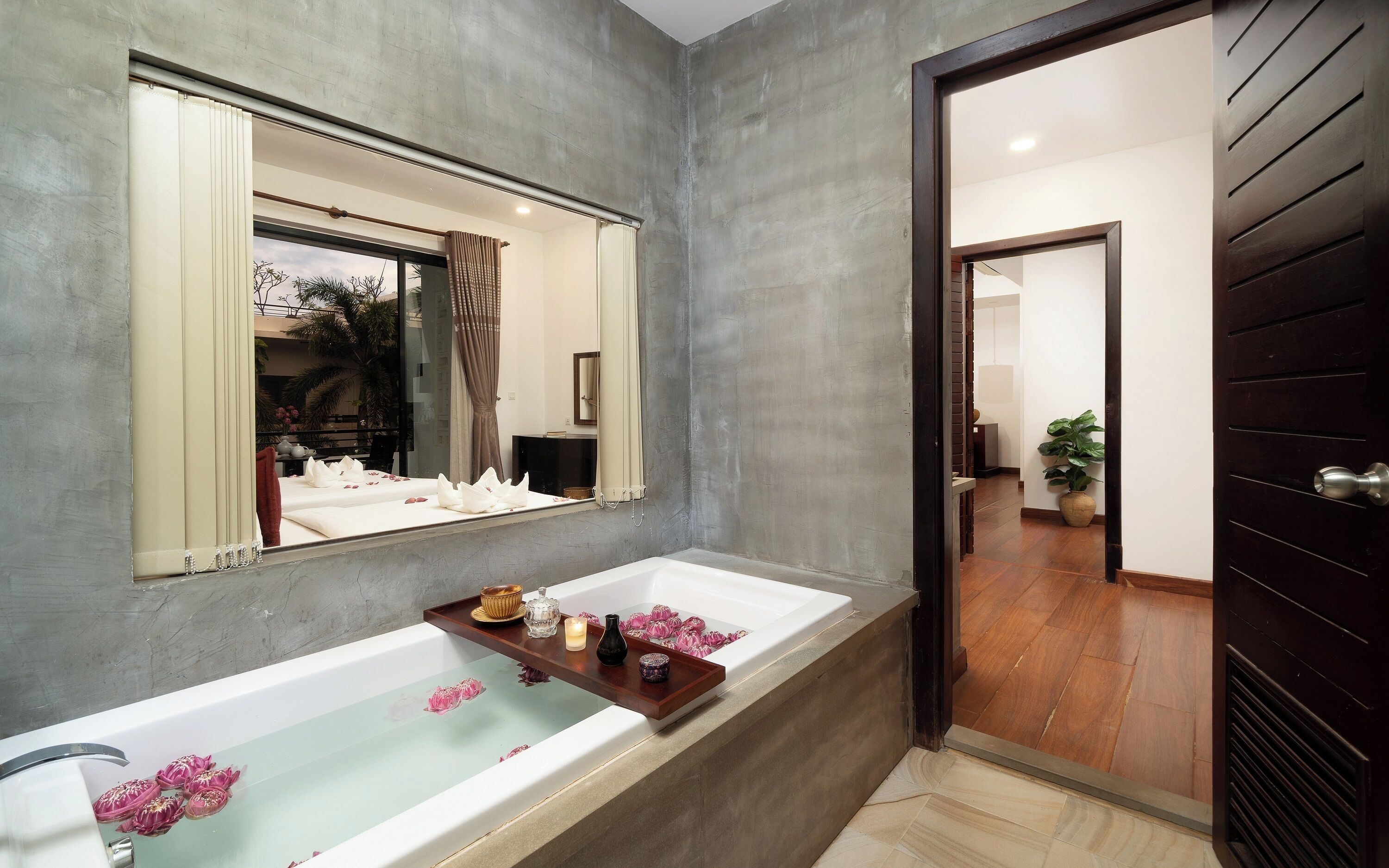 Un baño moderno con una bañera grande, un espejo y una bandeja de madera con artículos de aseo.