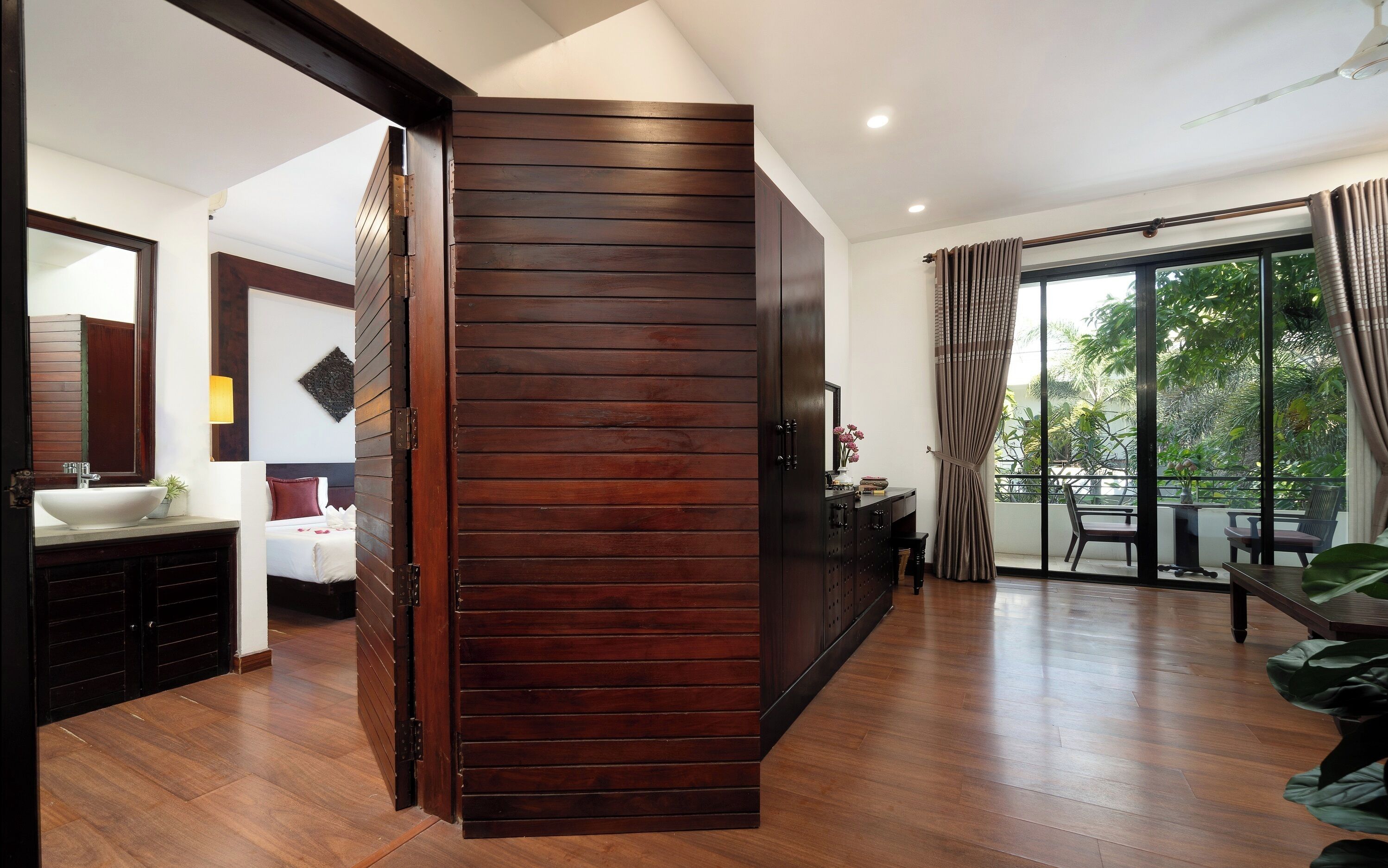 Ein modernes Wohnzimmer mit einer Holzwand, einem großen Fenster mit Vorhängen und einem Balkon mit Gartenmöbeln.