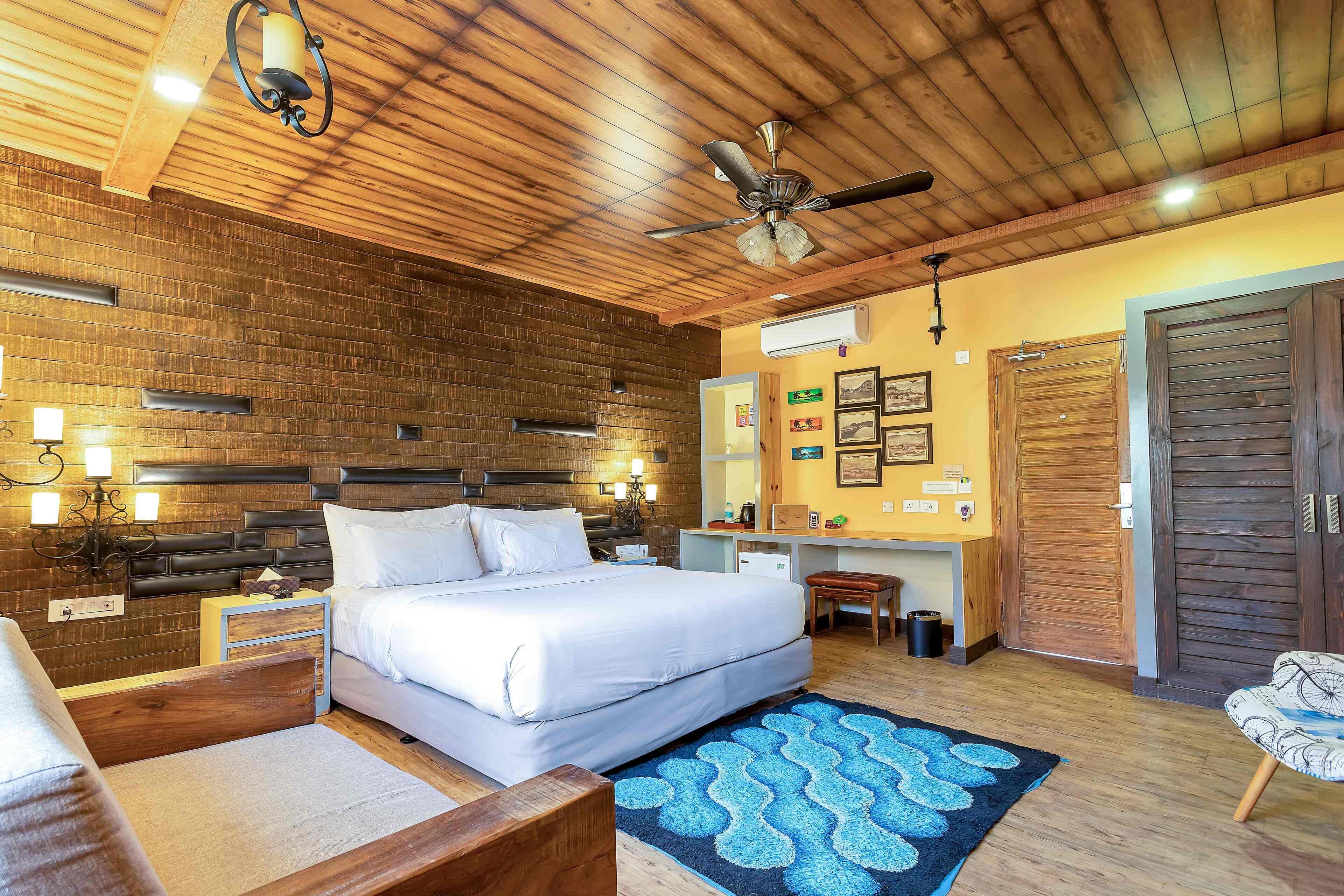 A bedroom with a large bed, wooden ceiling, a desk, and a chair.
