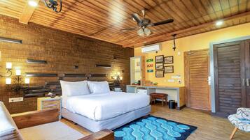 A bedroom with a large bed, wooden ceiling, a desk, and a chair.